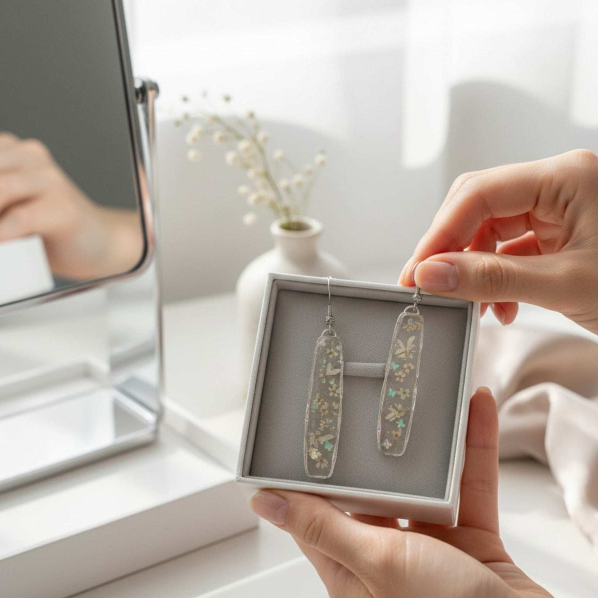 Long organic-edged Floral Butterfly drop earrings featuring tiny white spring flowers and miniature butterflies floating in clear resin.