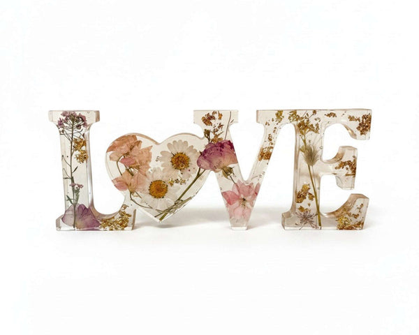Whispering Meadow LOVE resin word art with white daisies, blush pink and purple wildflowers, bunny tail, and gold leaf flakes