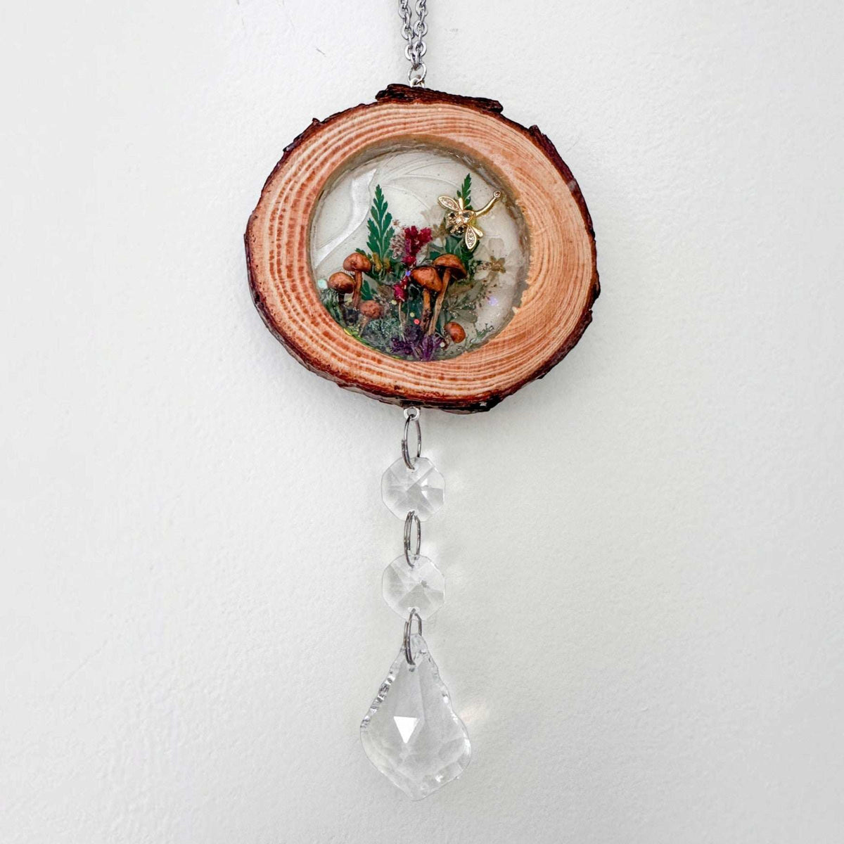 Suncatcher with a natural wood slice frame, miniature woodland botanicals in resin, and clear hanging crystal prisms