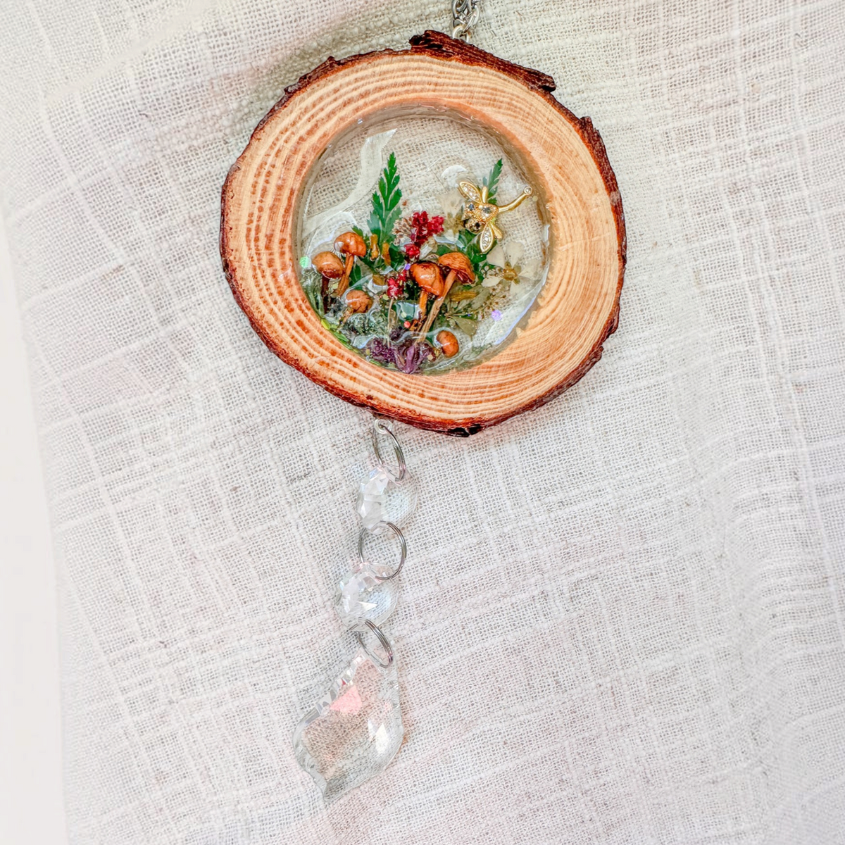 Suncatcher with a natural round wood slice, clear resin woodland scene, tiny mushrooms, greenery, dragonfly charm and crystal prisms
