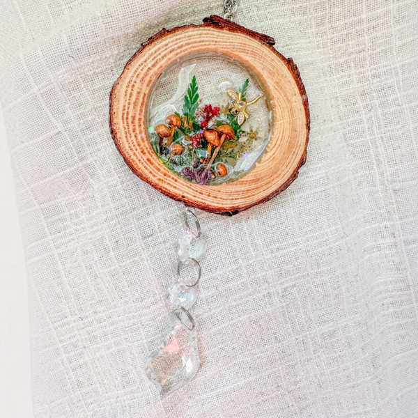 Suncatcher with a natural round wood slice, clear resin woodland scene, tiny mushrooms, greenery, dragonfly charm and crystal prisms
