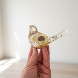 Resin bird ornament with a pressed yellow Sunflower, green botanicals, and gold leaf in a clear finish.