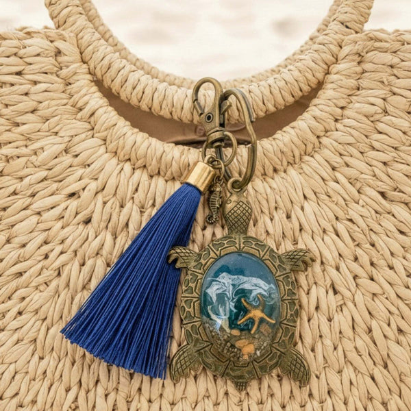 Sea turtle keychain in antique bronze with blue tassel and an ornate turtle charm holding ocean-toned resin and shell details
