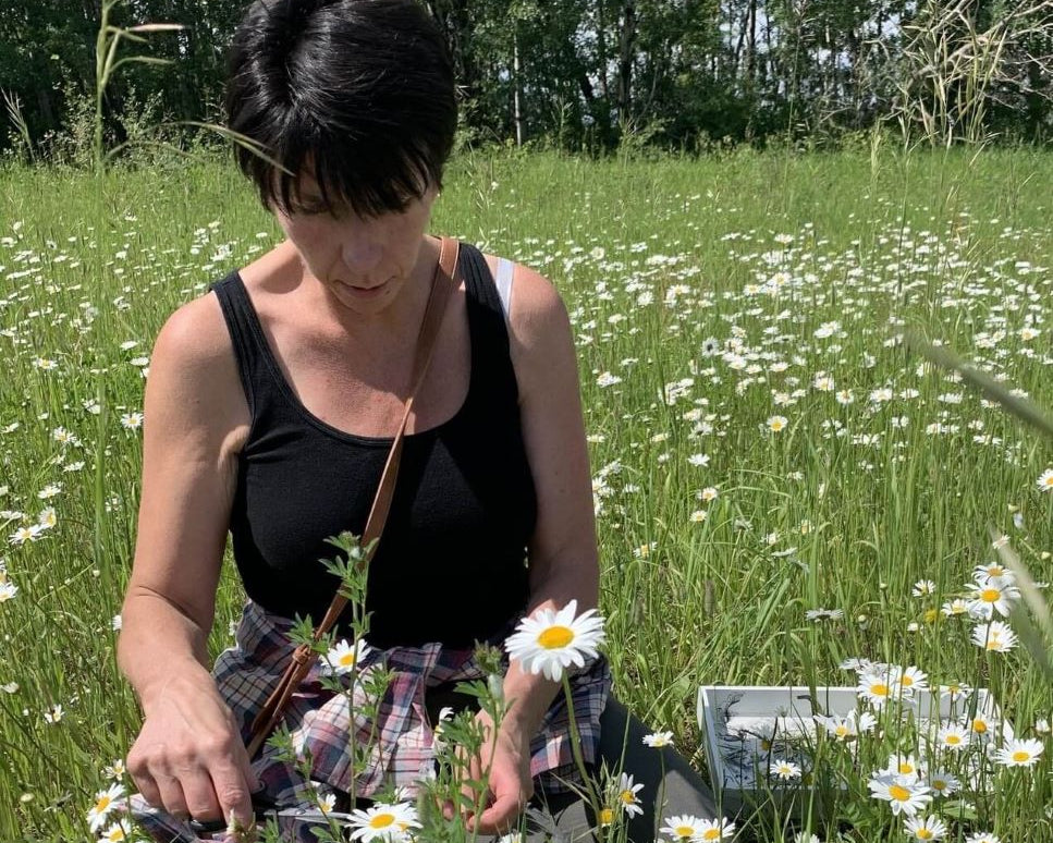 Person in a field of flowers with a box on the ground