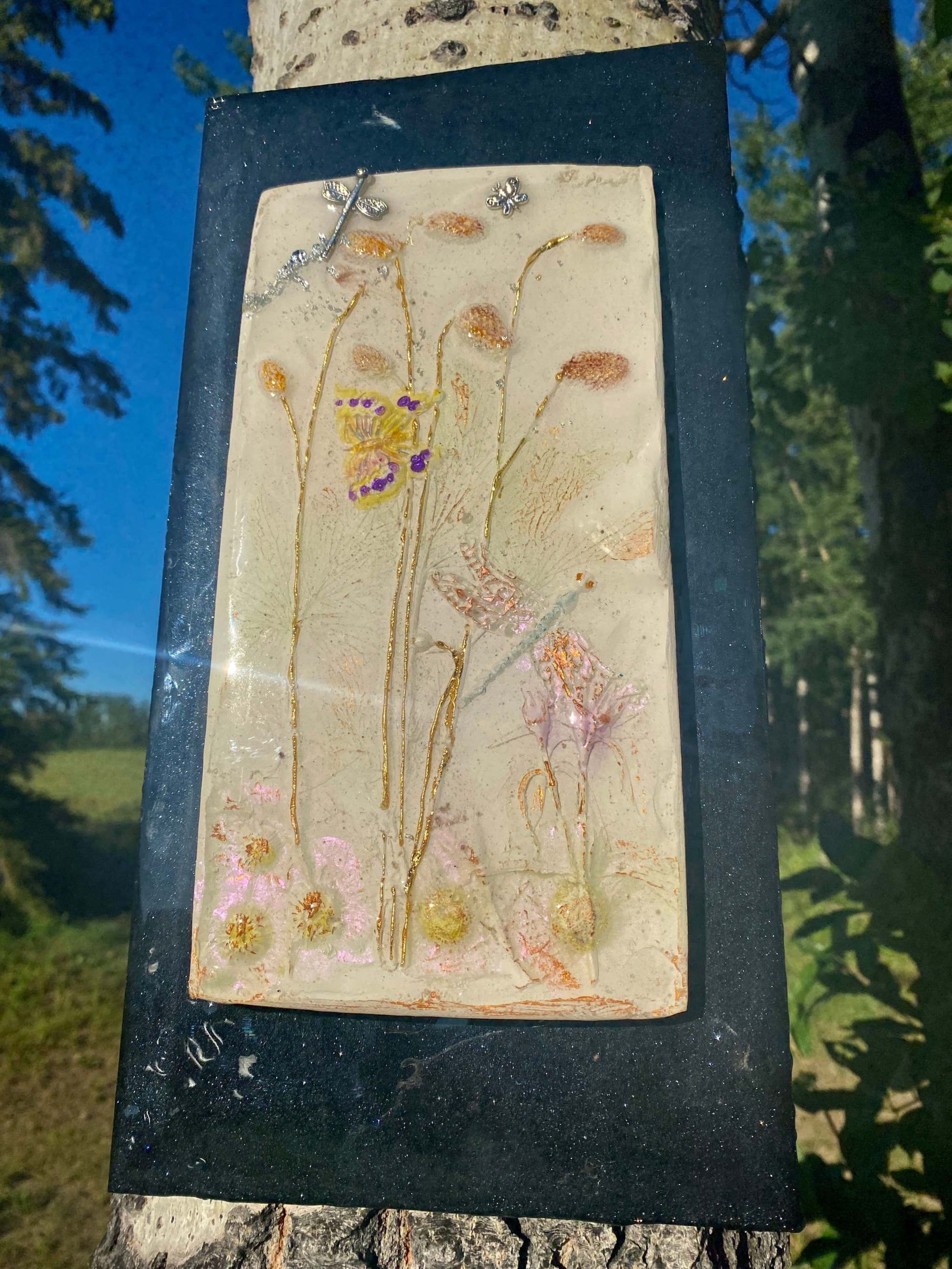 A "tile" with real botanicals pressed into clay and then  sealed with Epoxy Resin. A pretty butterfly with silver dragonflies and flowers  to show off the nature