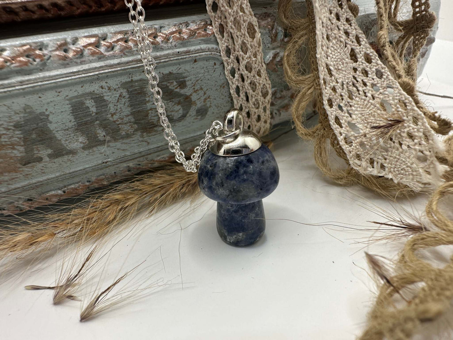 A Blue Howalite crystal mushroom hanging from a silver chain