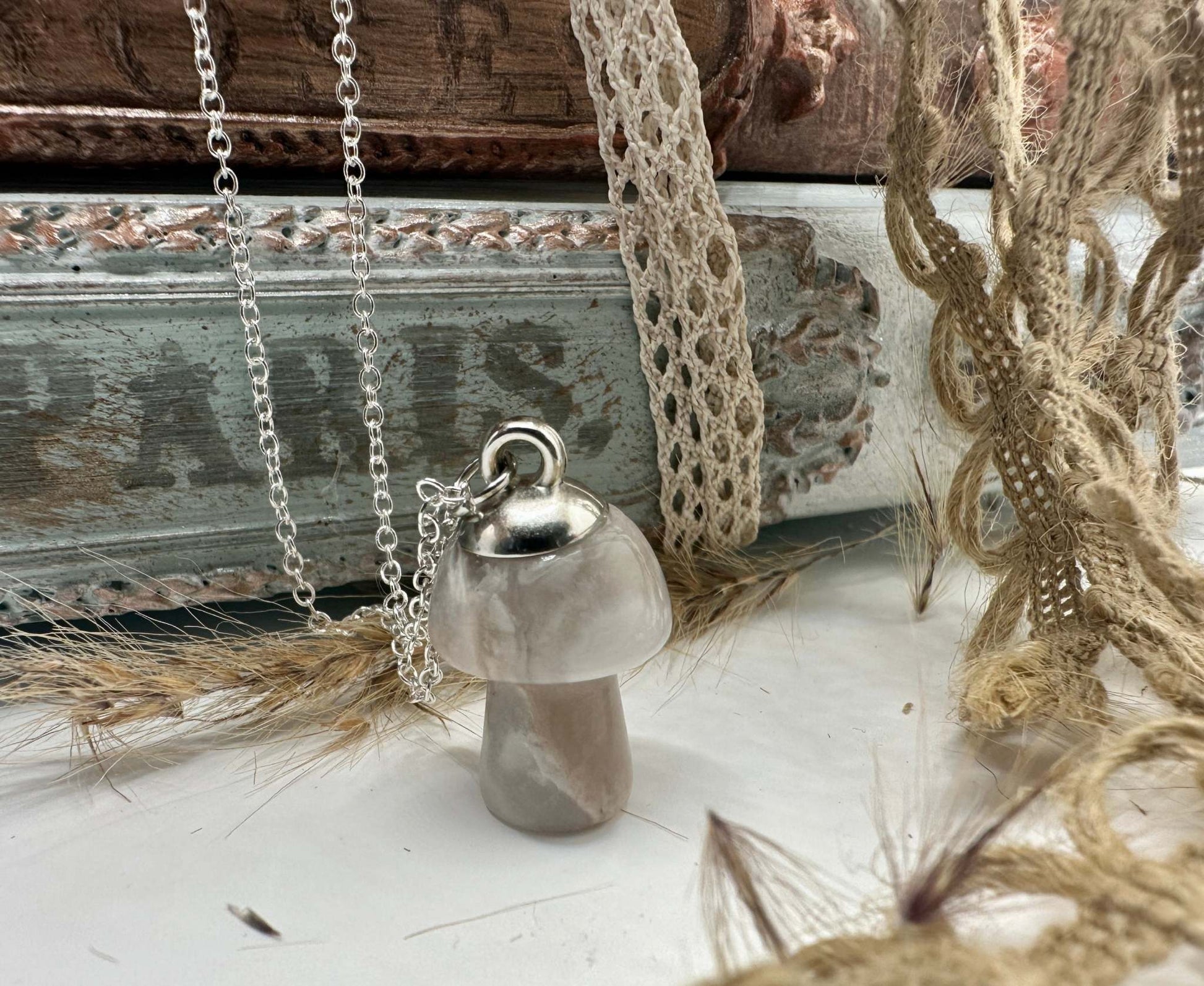 A flower agate mushroom shaped gemstone necklace hangs from a silver chain